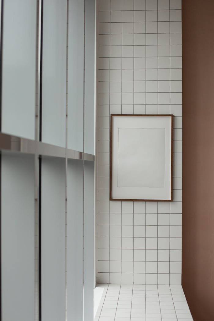 Elegant minimalist interior with white tiles and framed picture, showcasing modern design.