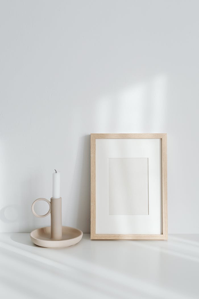 Elegant minimalist composition featuring a candle beside an empty wooden frame in soft light.