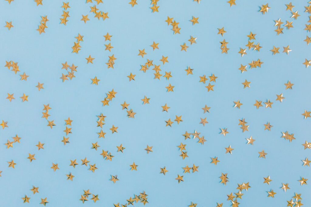 Gold star confetti scattered over a light blue surface, perfect for festive occasions.